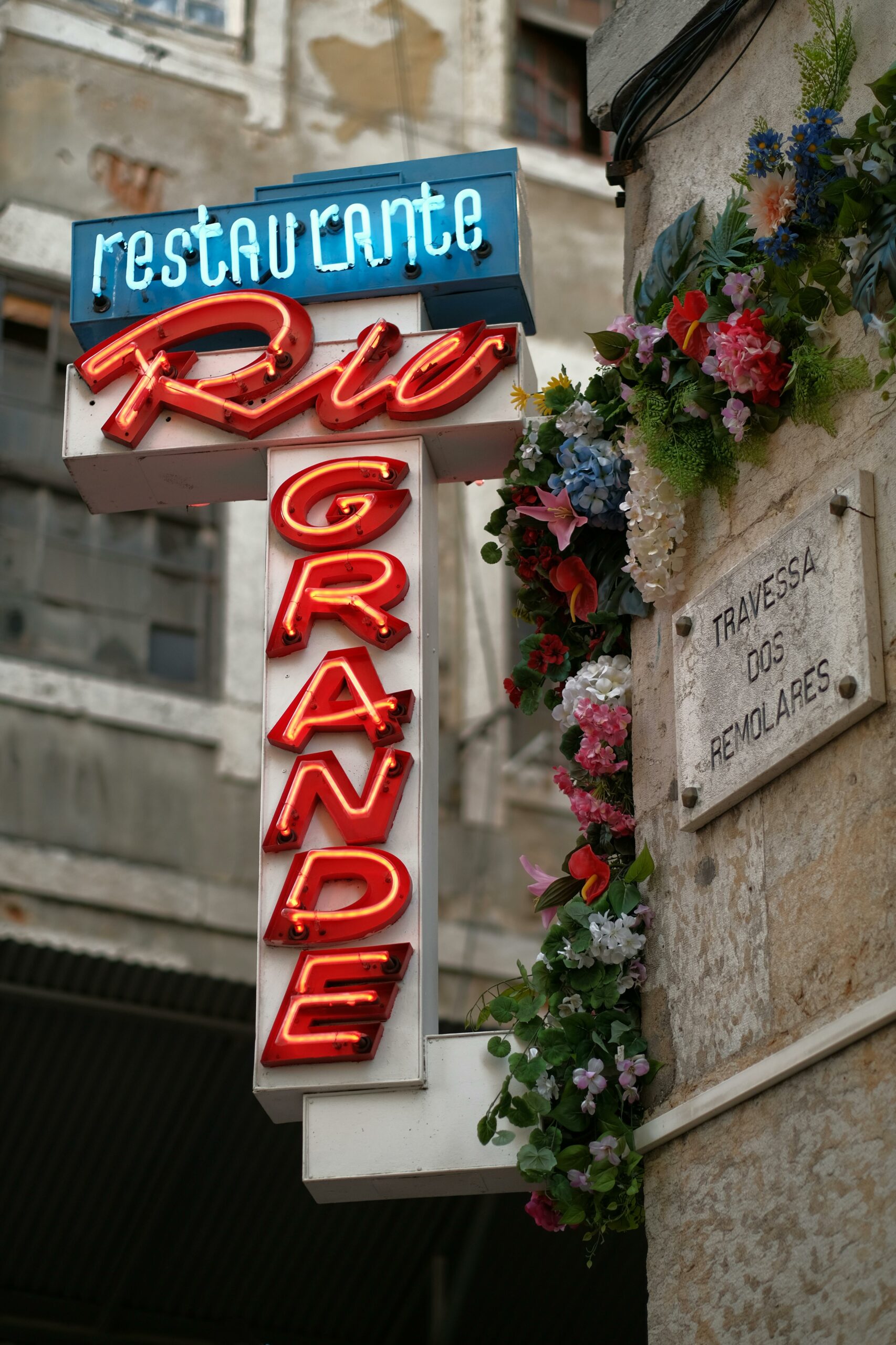 Vibrant neon sign of Rio Grande restaurant in Lisbon's charming streets.